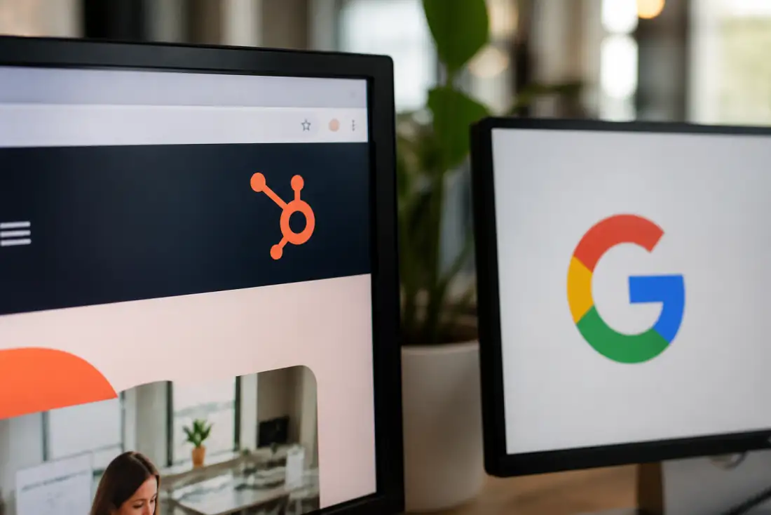 Desk with monitors showing Google and HubSpot in a marketing workspace